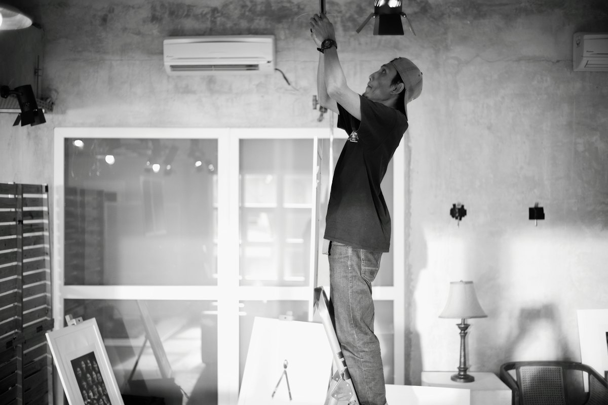 Electrician working on ceiling wiring from a ladder